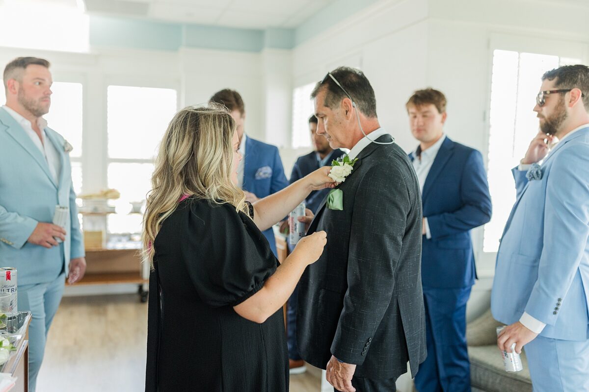 Wedding planner and coordinator pinning florals on the groomsmen 