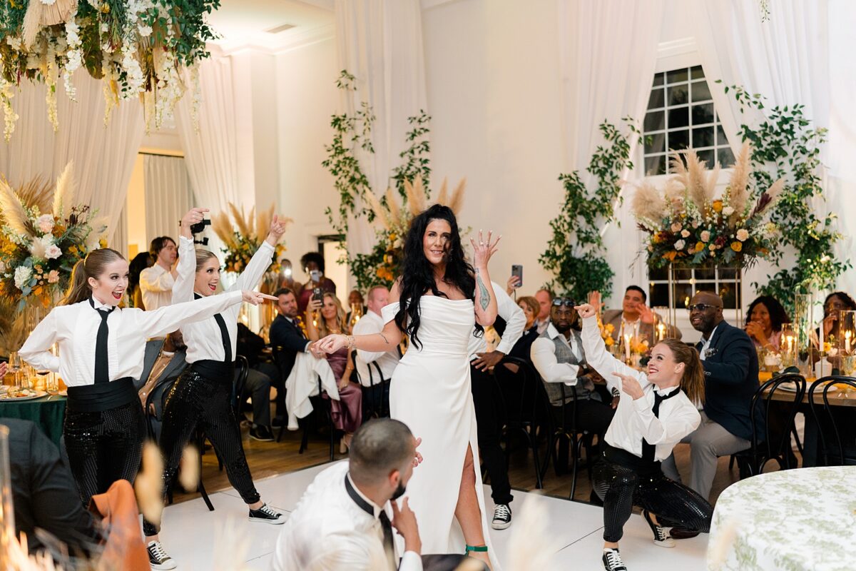 Bride joins surprise flash mob dance group at wedding reception in Kindred Wedding and Event Venue in Carolina Beach, NC. A wedding by Brittanie Raquel Events. 