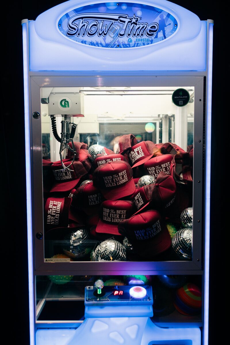 Custom hats as wedding favors inside a claw arcade game at wedding after party